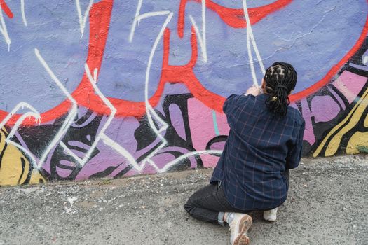Artiste de street art peignant une fresque colorée sur un mur à la Côte basque, mettant en valeur le style urbain.