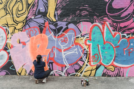 Artiste peignant un graffiti coloré sur un mur lors du festival Colorama Côte basque, mettant en avant le street art.