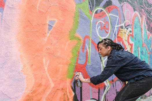 Artiste de street art peignant un mur coloré avec des sprays, illustrant le festival Colorama Côte basque.